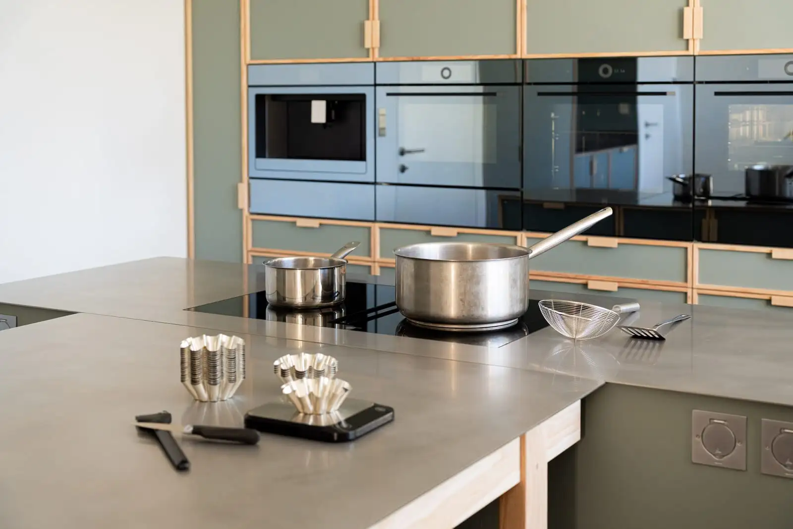Casseroles sur la plaque à induction et ustensiles prêts pour un atelier cuisine chez Qu4tre-Qu4rts