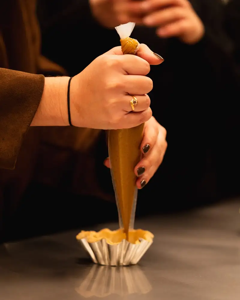 Participante garnissant un fond de tarte à la poche pendant un atelier pâtisserie à l'Atelier Qu4tre-Qu4rts, Bordeaux