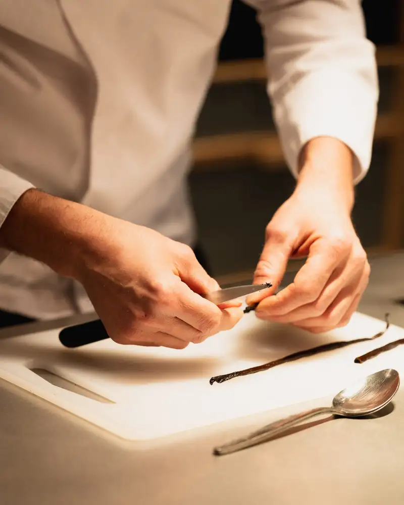 Mains d'un chef préparant une gousse de vanille sur le plan de travail de l'Atelier Qu4tre-Qu4rts, Bordeaux