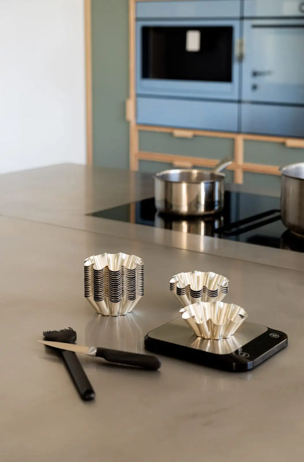 Moules à cannelés, balance et ustensiles de pâtisserie sur le plan de travail de l'Atelier Qu4tre-Qu4rts