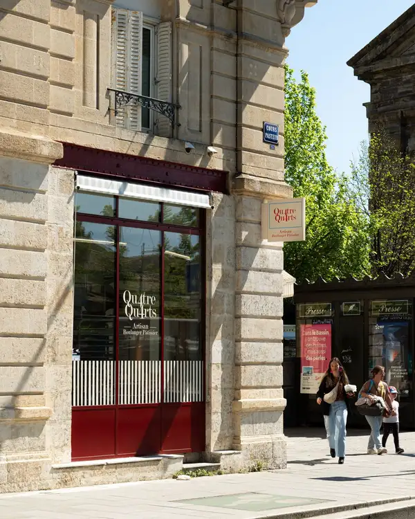 Boulangerie Qu4tre-Qu4rts à l'angle de la place de la Victoire à Bordeaux, façade en pierre et vitrine rouge