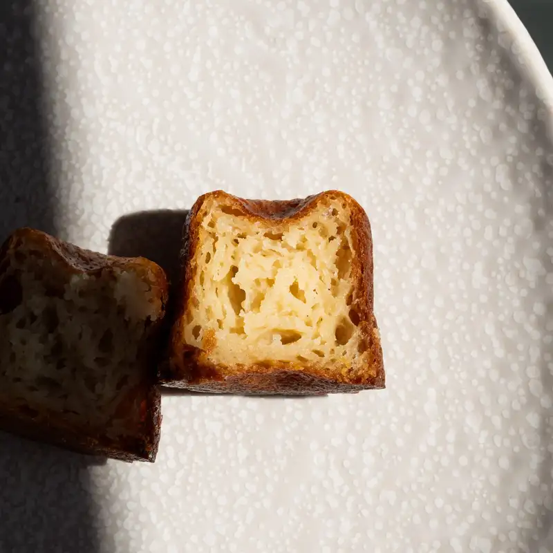 Cannelé coupé en deux, croûte caramélisée et cœur fondant, pâtisserie Quatre-Quarts à Bordeaux