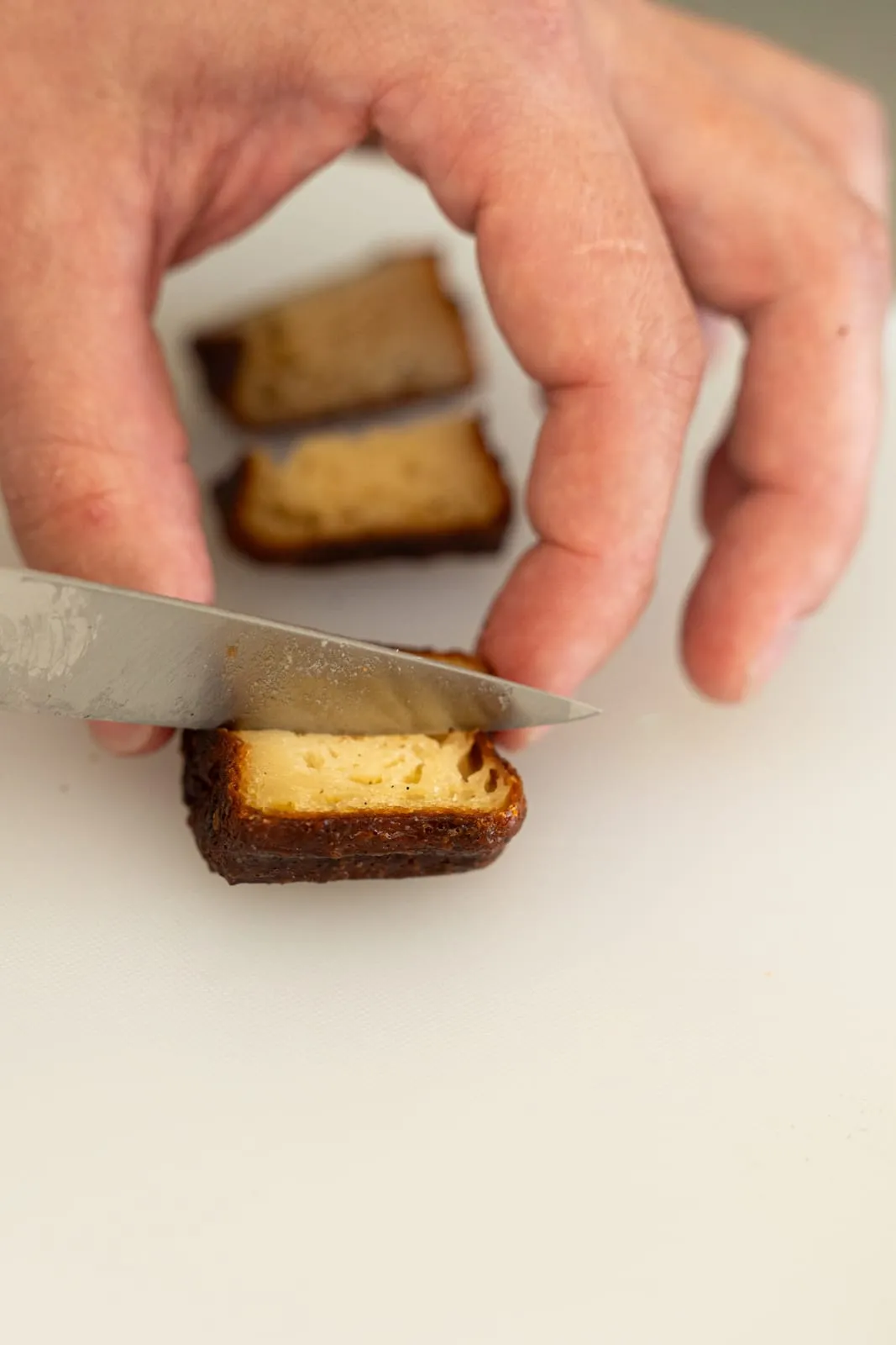Main coupant un cannelé en deux pendant la dégustation, cœur moelleux, Qu4tre-Qu4rts à Bordeaux