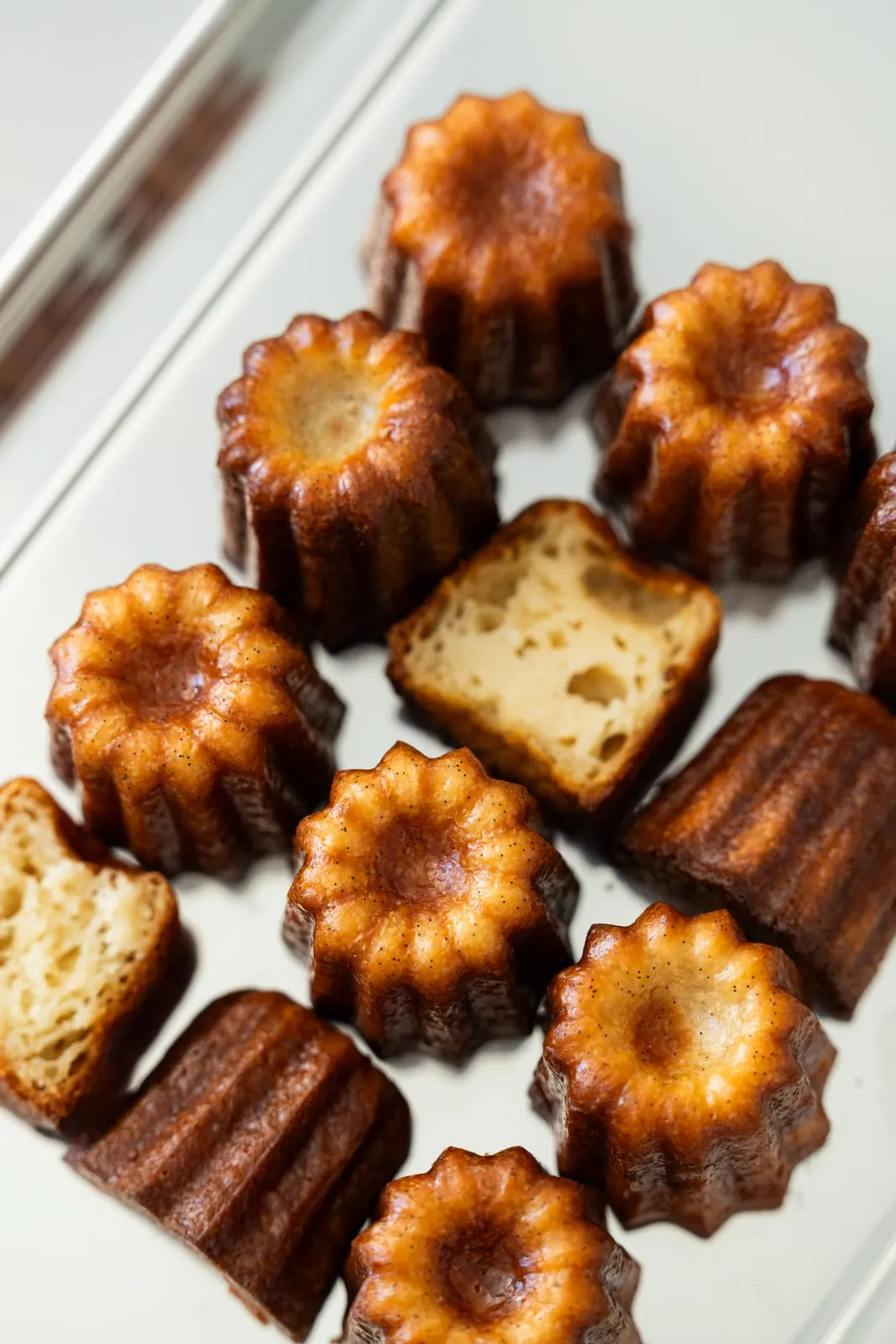 Cannelés bordelais entiers et coupés vus de dessus, croûte dorée et cœur fondant, Qu4tre-Qu4rts Bordeaux