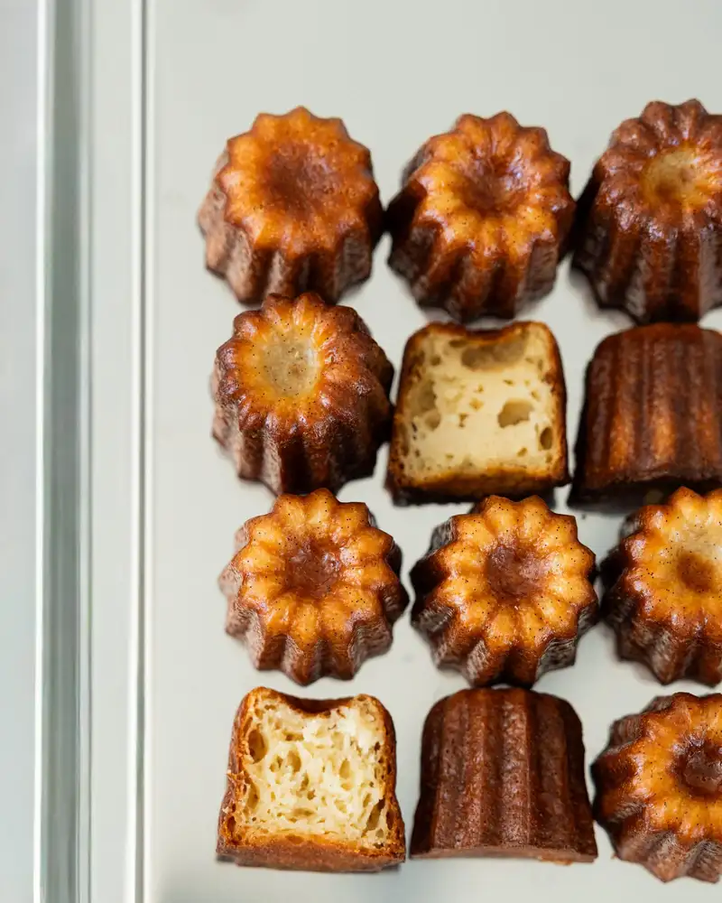 Cannelés bordelais alignés vus de dessus, dont un coupé, pâtisserie Quatre-Quarts à Bordeaux