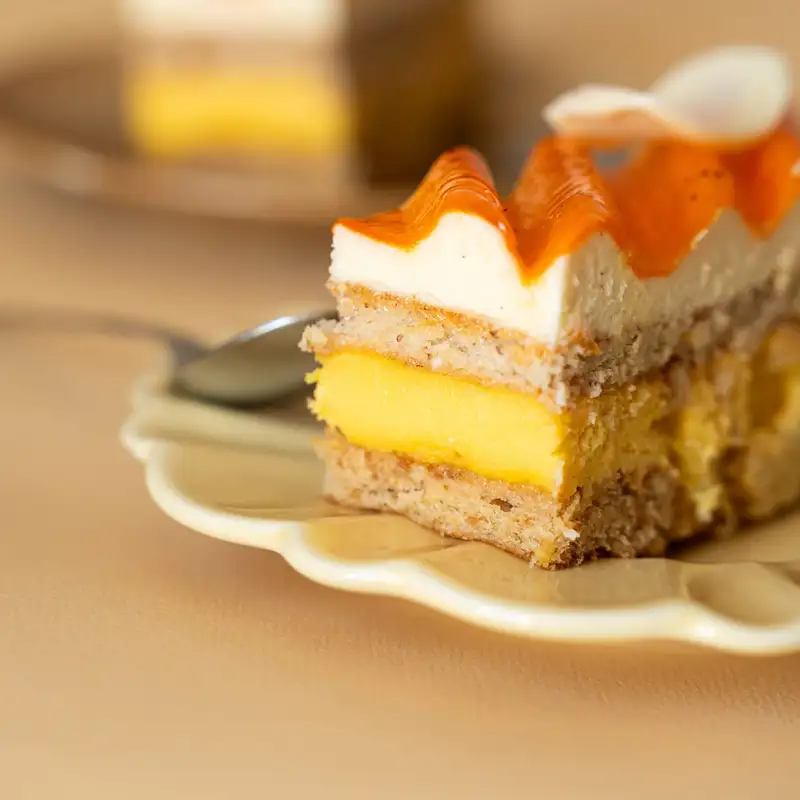 Part d'entremets aux couches de crème et de biscuit, nappage orangé, pâtisserie Quatre-Quarts à Bordeaux