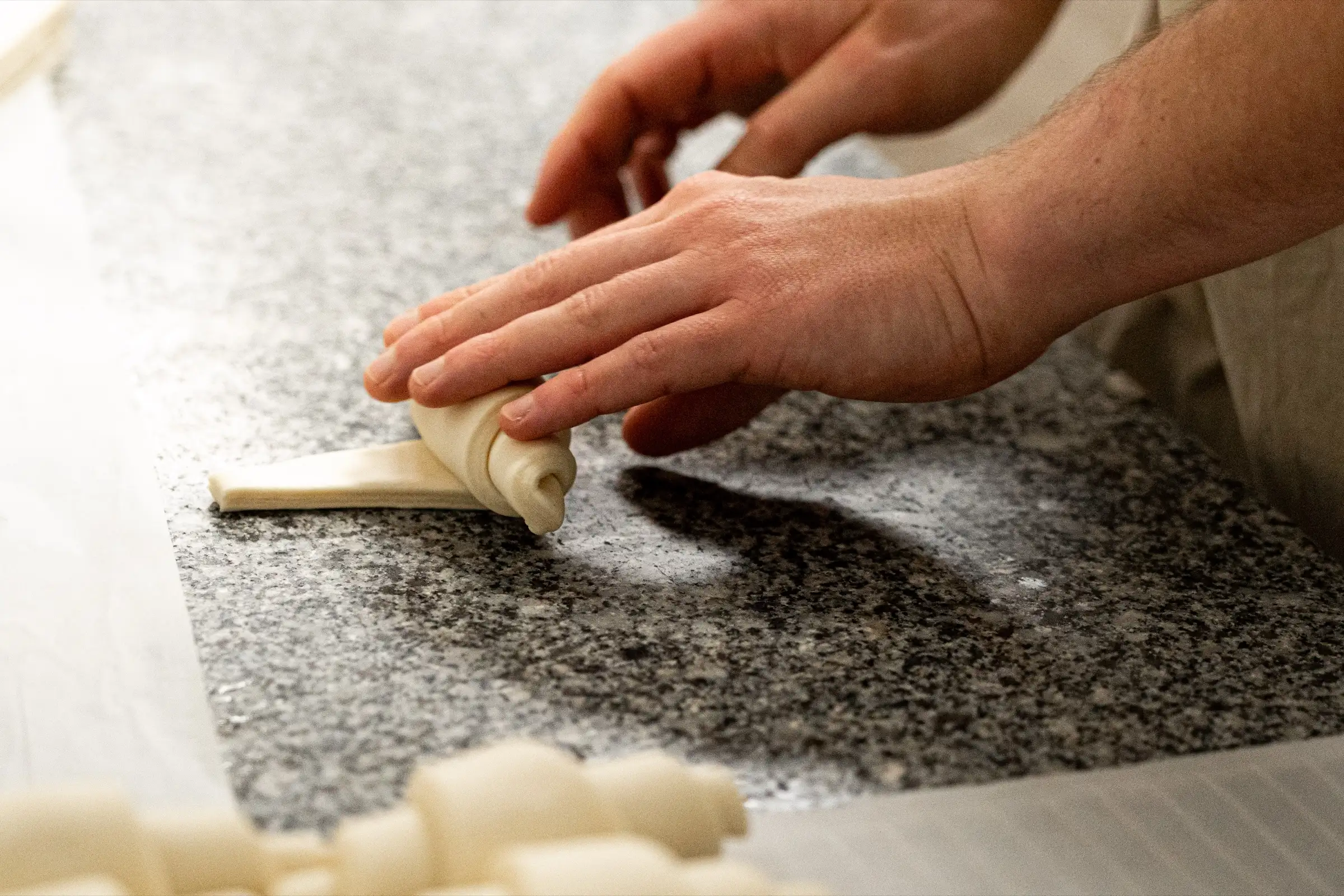 Mains d'un boulanger Qu4tre-Qu4rts roulant un croissant sur le plan de travail, Bordeaux