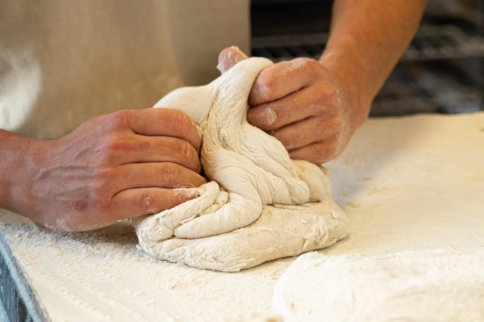 Boulanger travaillant à la main une pâte au levain naturel sur le plan fariné, boulangerie Qu4tre-Qu4rts à Bordeaux