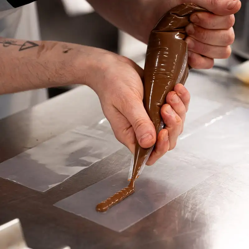 Pâtissier pochant du chocolat à la poche au laboratoire Qu4tre-Qu4rts de Bassens
